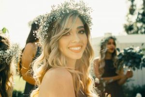 young woman at a wedding with a flower crown smiling