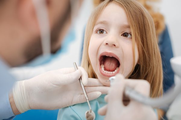 young girl opening her mouth for the dentist to look inside